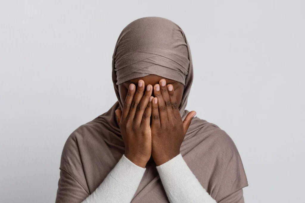 Femme voilée, le visage dans les mains, traversant une période difficile